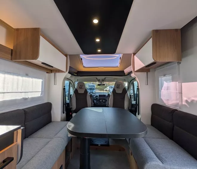 Intérieur spacieux d'un camping-car moderne avec table et banquettes grises