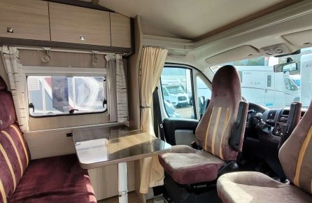 Intérieur d'un camping-car avec sièges et table, ambiance confortable.