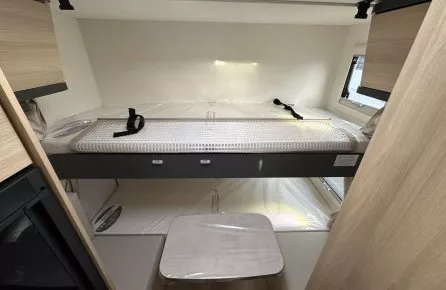 Intérieur d'un camping-car avec lit superposé et rangements en bois clair.