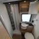 Salle de bain compacte avec douche, lavabo et toilettes dans un camping-car moderne.