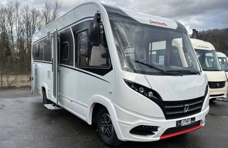 Camping-car Dethleffs blanc stationné sur un parking, ciel nuageux en arrière-plan.