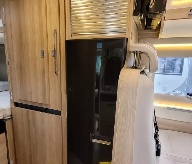 Intérieur d'un camping-car avec placards en bois et siège en cuir blanc