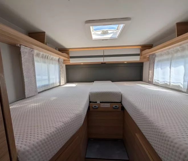 Intérieur d'une caravane avec lits jumeaux et hublot au plafond