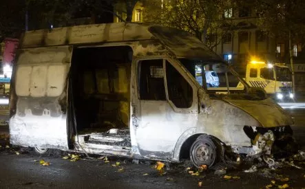 Fourgon incendié sur une route la nuit, avec dépanneuse en arrière-plan