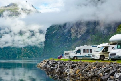 Camping-cars stationnés au bord d'un fjord norvégien avec montagnes et nuages