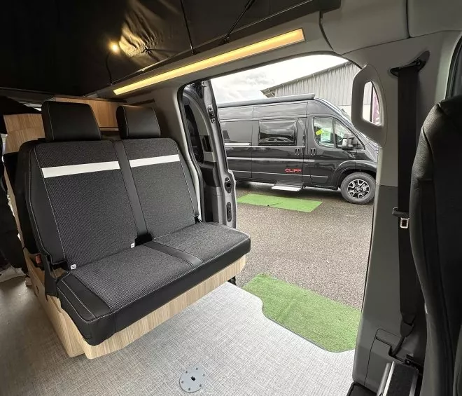 Intérieur d'un van aménagé avec sièges et espace de rangement, van noir à l'extérieur