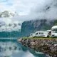 Camping-cars stationnés au bord d'un fjord norvégien avec montagnes et nuages
