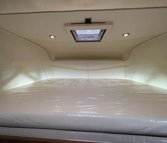 Espace de couchage dans un camping-car avec matelas et éclairage intégré