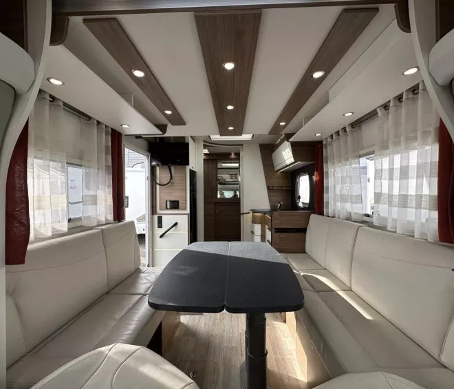 Intérieur spacieux et moderne d'un camping-car avec salon et cuisine équipée.