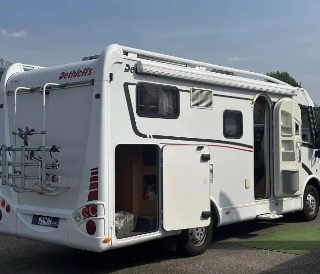 Camping-car Dethleffs stationné avec porte ouverte et porte-vélos à l'arrière.