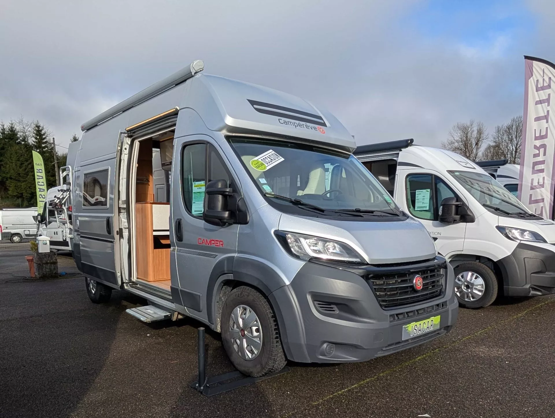 Camping-car Camperêve stationné sur un parking, porte latérale ouverte