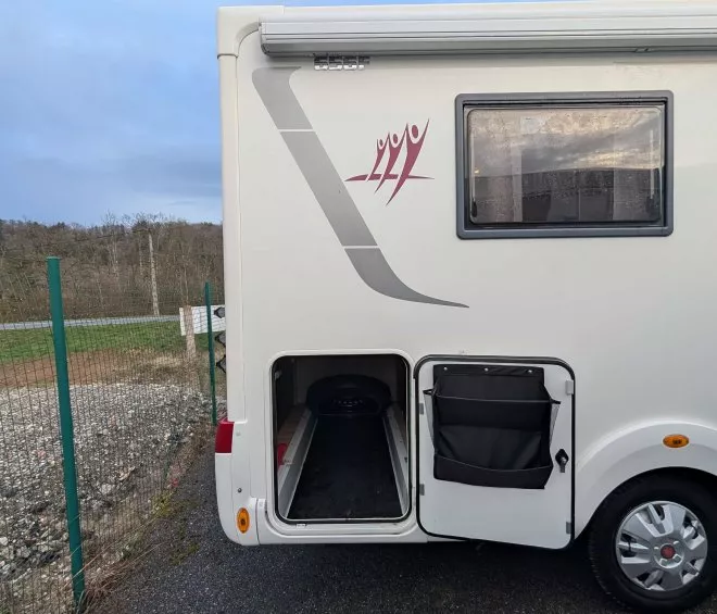 Coffre ouvert d'un camping-car stationné sur un parking