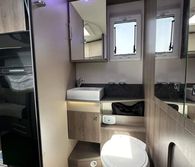 Salle de bain moderne dans un camping-car avec toilettes et lavabo intégrés.