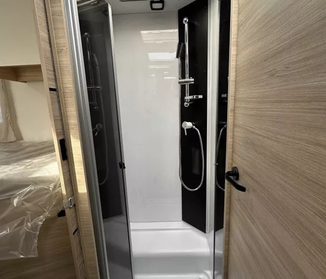 Douche moderne dans un camping-car avec parois vitrées et puits de lumière.