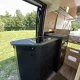 Intérieur d'un camping-car moderne avec cuisine équipée, vue sur l'extérieur verdoyant.