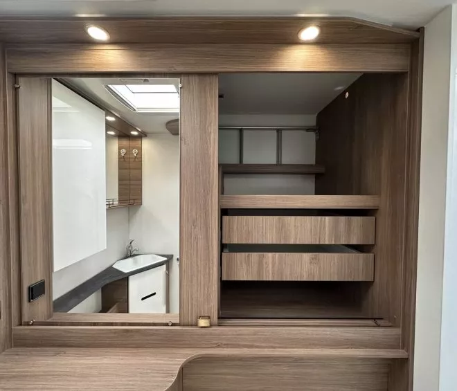 Intérieur d'un meuble en bois avec tiroirs et lavabo intégré, éclairage LED au plafond.