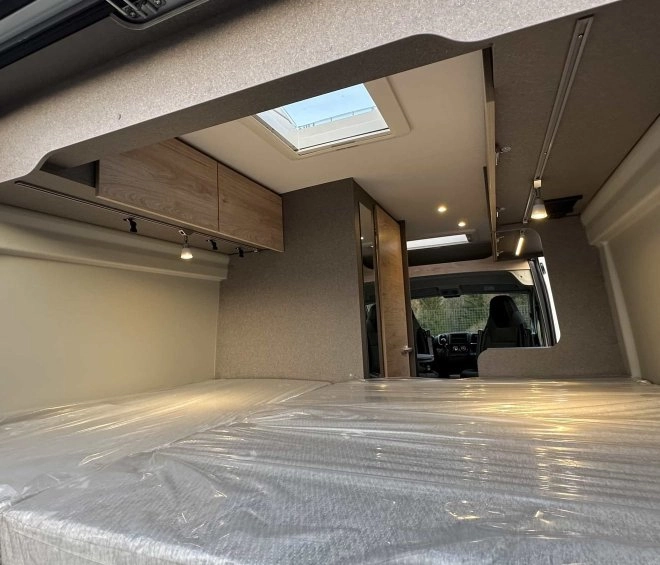 Intérieur d'un van aménagé avec lit et rangements en bois