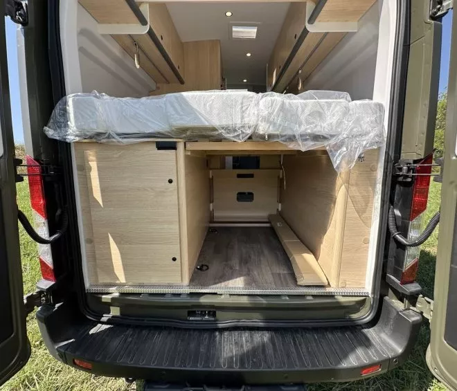 Intérieur d'un van aménagé avec lit et rangements en bois clair