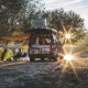 Camping-car aménagé au bord d'un lac au coucher du soleil, personne assise à côté