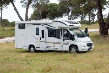 Camping-car stationné dans un champ entouré d'arbres