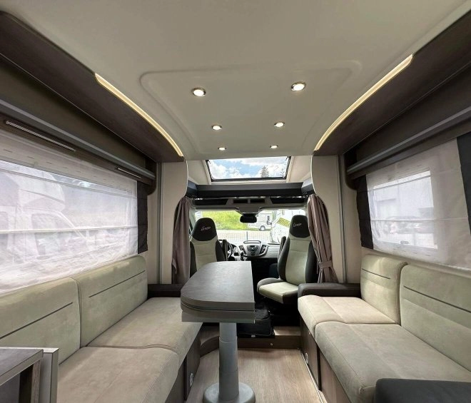 Intérieur spacieux d'un camping-car moderne avec sièges et table.