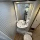 Salle de bain compacte avec lavabo, miroir et toilettes dans un camping-car moderne.