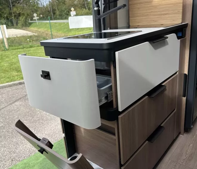 Cuisine compacte intégrée dans un van aménagé avec évier et rangements ouverts
