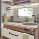 Cuisine compacte de camping-car avec évier, plaques de cuisson et rangements ouverts.