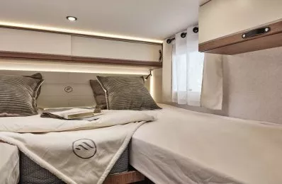 Intérieur d'une chambre de camping-car avec lit double et éclairage LED.