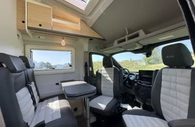 Intérieur d'un camping-car moderne avec sièges et table, vue sur la nature