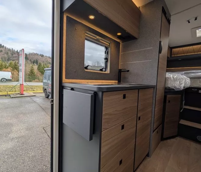 Intérieur d'un van aménagé avec cuisine en bois et éclairage LED