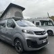 Van Opel Crosscamp avec toit relevable sur un parking de camping-cars.
