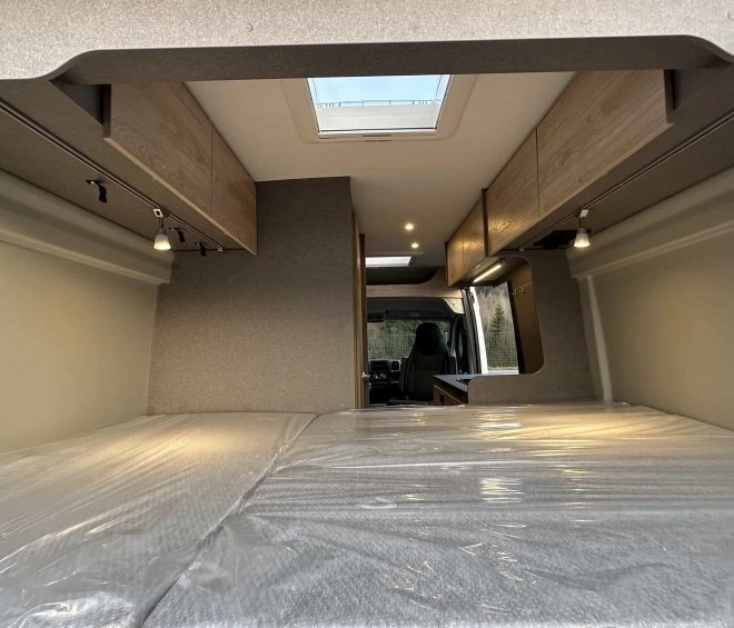 Intérieur d'un van aménagé avec lit et rangements en bois