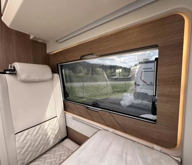 Intérieur d'un camping-car avec siège beige et fenêtre panoramique.