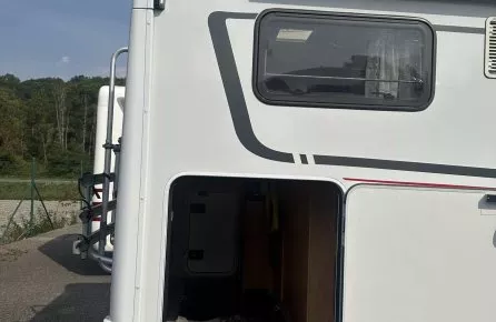 Vue arrière d'un camping-car avec soute ouverte, marque Dethleffs visible