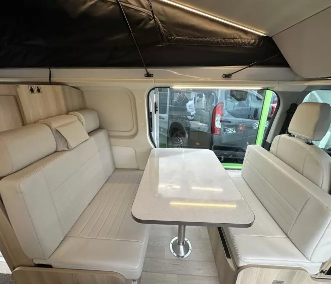 Intérieur d'un van aménagé avec banquettes et table pliante