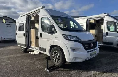 Camping-car blanc stationné avec porte ouverte, ciel nuageux