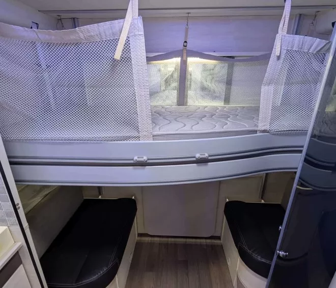 Intérieur d'un camping-car avec lit superposé et sièges en cuir noir