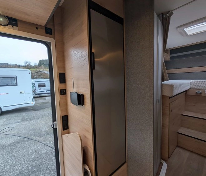 Intérieur d'un camping-car moderne avec mobilier en bois et réfrigérateur intégré