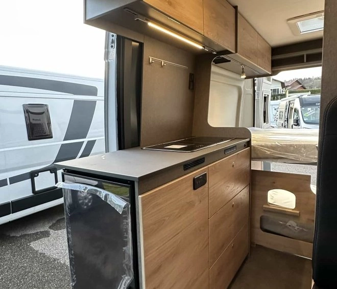 Intérieur d'un van aménagé avec cuisine moderne et rangements en bois clair.