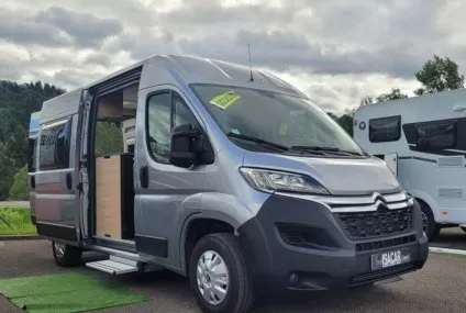 Fourgon aménagé Citroën gris stationné sur un parking, porte latérale ouverte