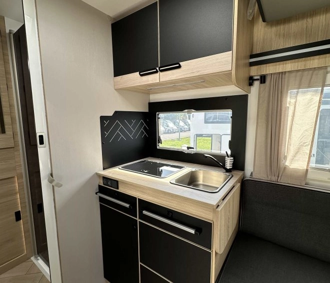 Intérieur moderne de cuisine de camping-car avec évier et rangements noirs et bois.