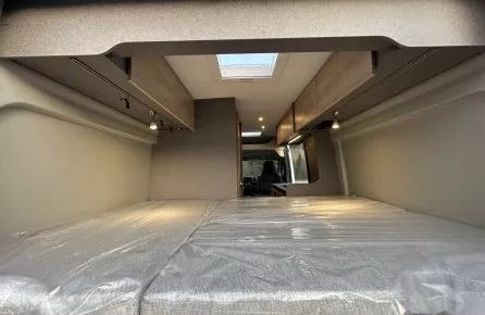 Intérieur d'un van aménagé avec lit double et rangements en bois clair