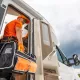 Technicien en uniforme orange inspectant un camping-car avec une trousse à outils