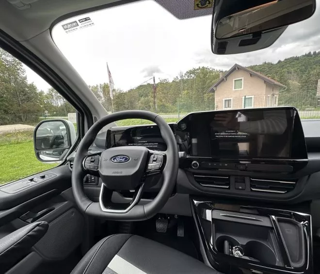 Intérieur d'un véhicule Ford avec tableau de bord moderne et vue extérieure sur une maison