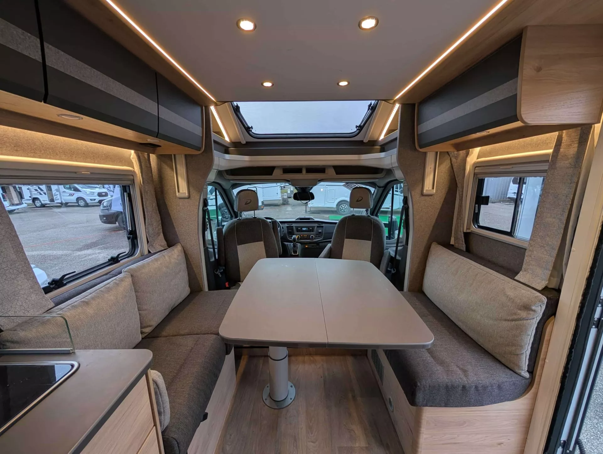 Intérieur d'un camping-car moderne avec table et banquettes grises