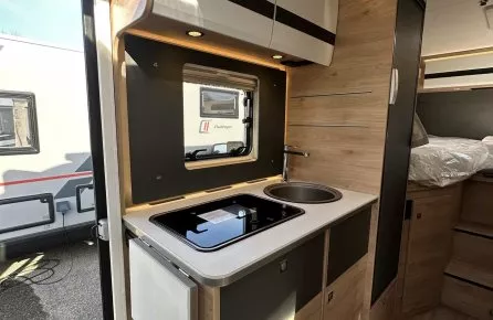 Intérieur d'une caravane avec kitchenette moderne et rangements en bois clair.