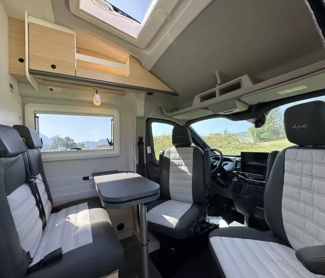 Intérieur d'un camping-car moderne avec sièges et table, vue sur la nature