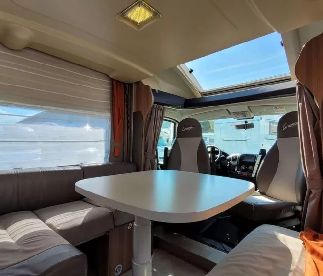 Intérieur d'un camping-car avec table et sièges en cuir, lumière naturelle.