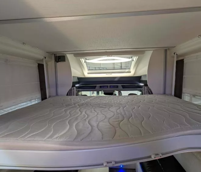 Lit escamotable dans un camping-car moderne avec puits de lumière
